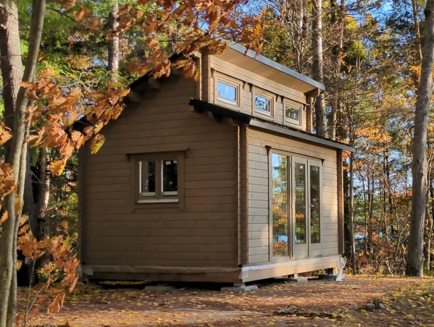 Small wooden cabin nestled among trees with autumn foliage