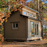 Small wooden cabin nestled among trees with autumn foliage