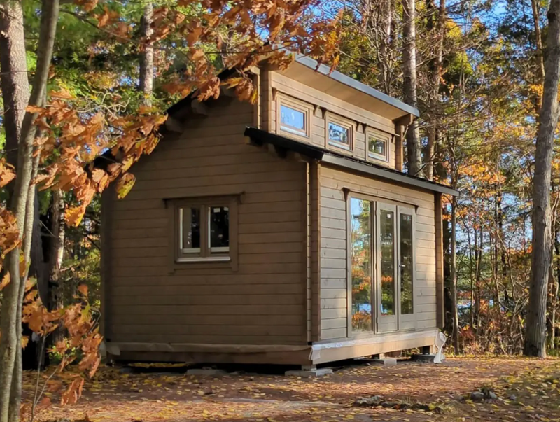Small wooden cabin nestled among trees with autumn foliage