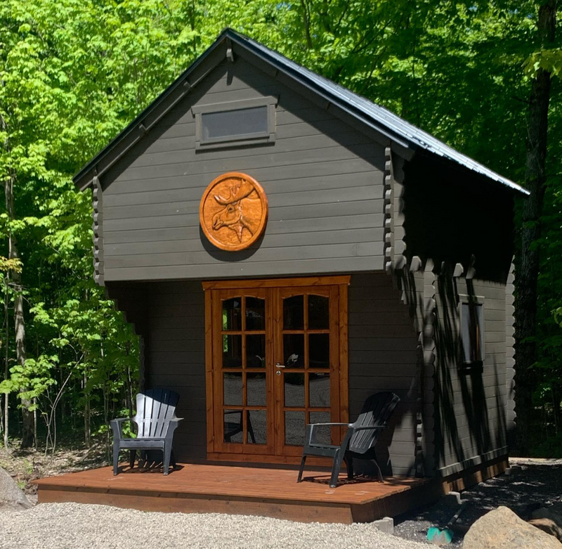 Small cabin with wooden door and deck in a forest setting